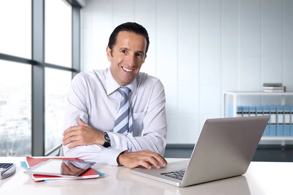 Hombre de negocios que trabaja en el ordenador portátil sentado en el escritorio mirando confiado — Foto de Stock