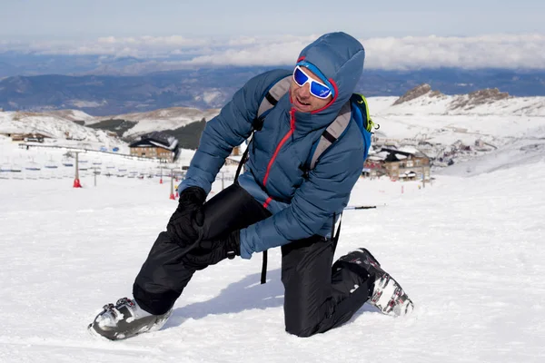 Homme couché sur la neige froide après l'accident de ski tenant son genou blessé dans la douleur à la station Sierrna Nevada — Photo