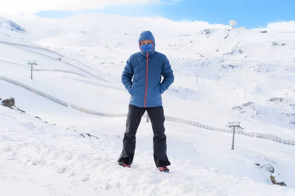 man with hood and scarf looking frozen on snow mountain at winter landscape