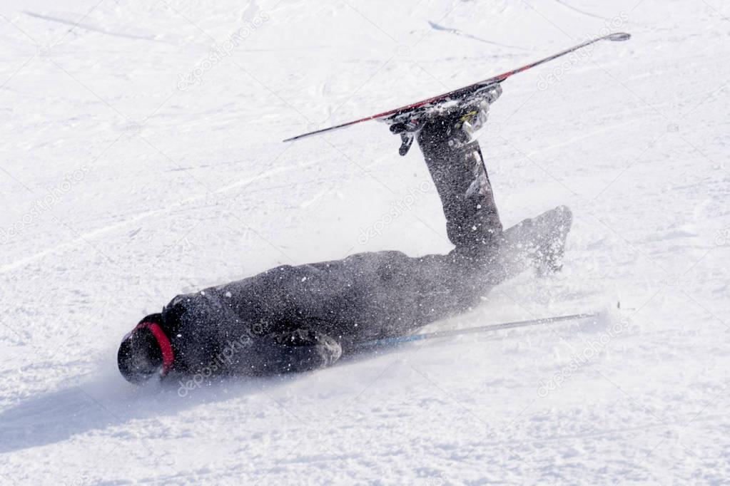 man falling on cold snow in ski crash at Sierrna Nevada resort in Spain in winter sport accident concept