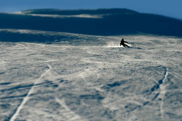 Silhueta retroiluminada do homem em ação praticando esqui indo rápido e agressivo para baixo neve inclinação inverno esporte — Fotografia de Stock