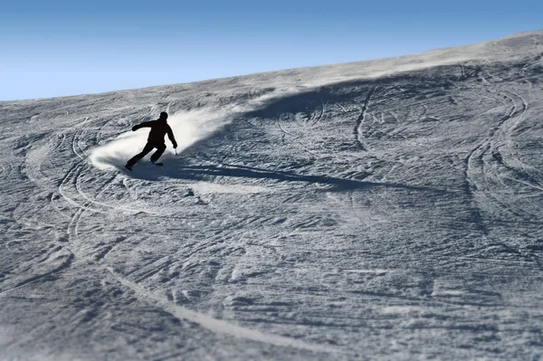 Silhouette rétroéclairée de l'homme en action pratiquant le ski en descendant rapidement et agressivement la pente de neige sport d'hiver — Photo