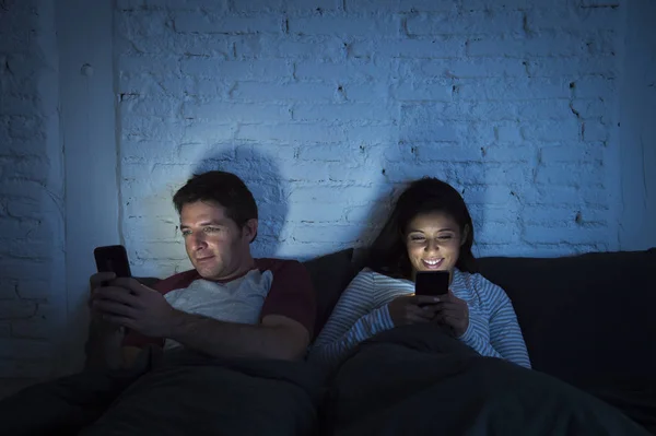 Couple at home in bed late at night using mobile phone in relationship communication problem — Stock Photo, Image