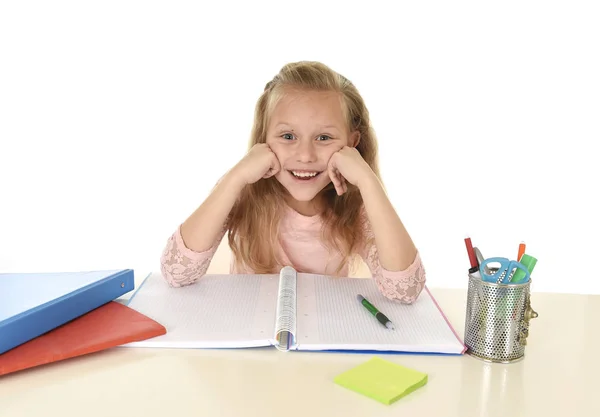 Bela estudante com cabelo loiro sorrindo feliz sentado na mesa fazendo lição de casa isolado no branco — Fotografia de Stock