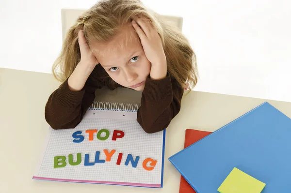 Depressief jong schoolmeisje met stop pesten tekst op notebook hulpeloos en bang als slachtoffer van pesten — Stockfoto