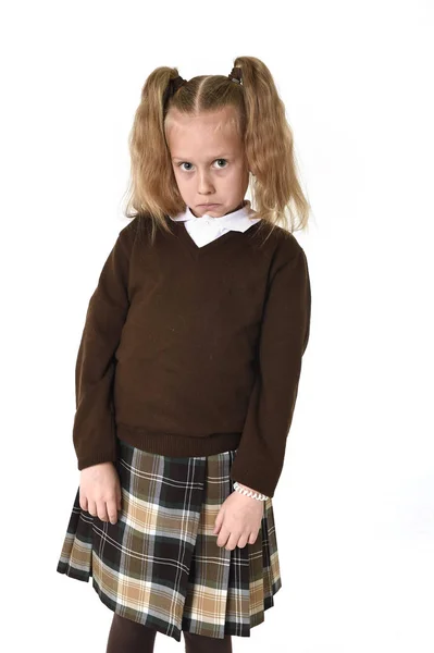 Pequeña colegiala con hermoso pelo rubio en uniforme escolar buscando tímido y tímido — Foto de Stock