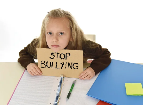 schoolgirl scared in stress holding paper with text stop bullying desperate asking for help
