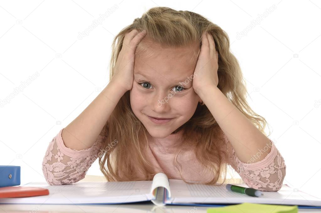 beautiful schoolgirl with blond hair smiling happy sitting on desk doing homework isolated on white