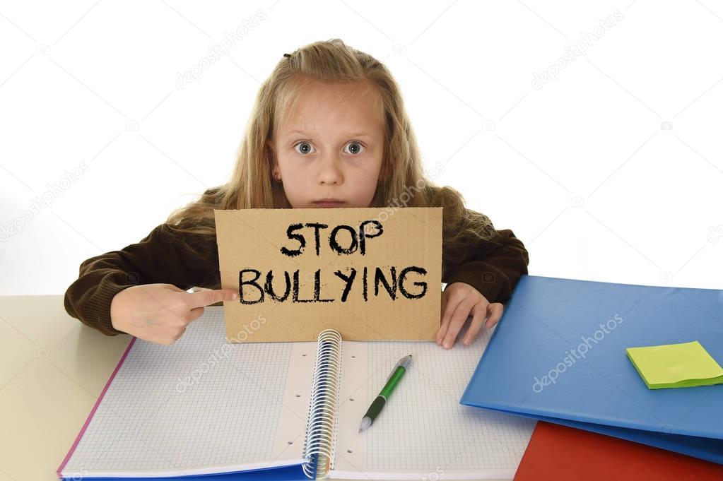  schoolgirl scared in stress holding paper with text stop bullying desperate asking for help