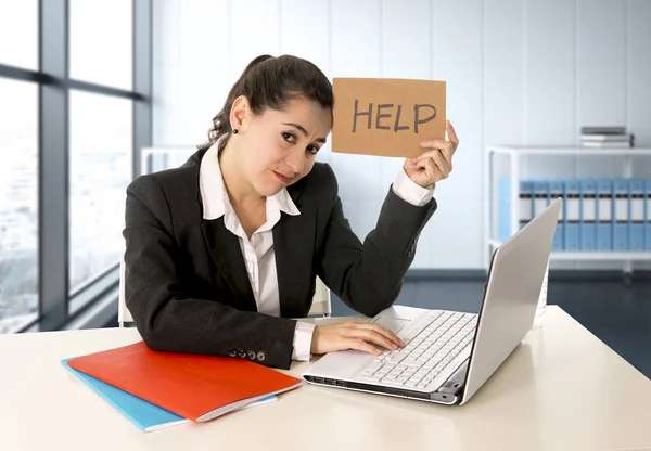Mujer vistiendo un traje de negocios trabajando en su computadora portátil sosteniendo un cartel de ayuda sentado en la oficina moderna —  Fotos de Stock
