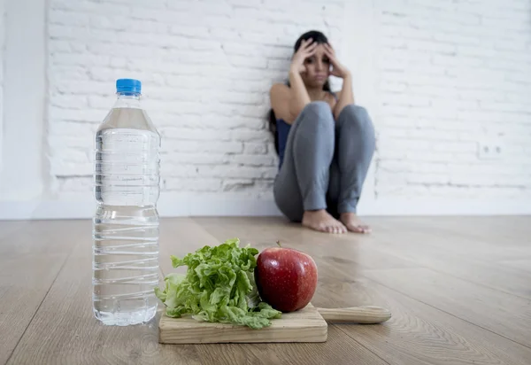 Жінка або дівчина-підліток, що сидить на землі одна хвилюється вдома, страждаючи від харчування, що їсть розлад — стокове фото