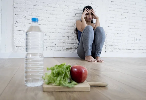 Frau oder Teenagermädchen, die allein auf dem Boden sitzen und zu Hause an einer Essstörung leiden — Stockfoto