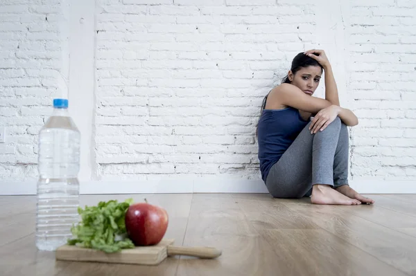 Mujer o niña adolescente sentada en el suelo sola preocupada en casa sufriendo un trastorno alimenticio nutricional — Foto de Stock