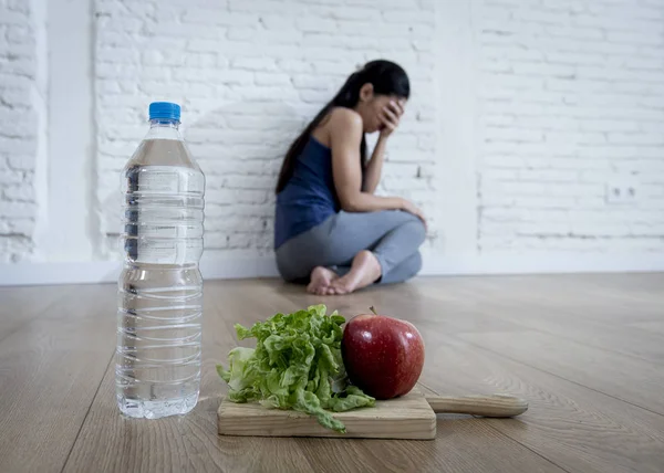 Жінка або дівчина-підліток, що сидить на землі одна хвилюється вдома, страждаючи від харчування, що їсть розлад — стокове фото