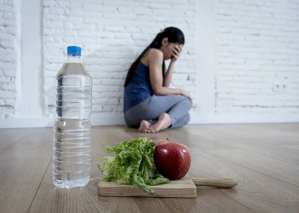 Frau oder Teenagermädchen, die allein auf dem Boden sitzen und zu Hause an einer Essstörung leiden — Stockfoto