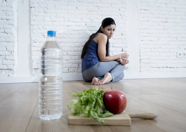 Mujer o niña adolescente sentada en el suelo sola preocupada en casa sufriendo un trastorno alimenticio nutricional — Foto de Stock