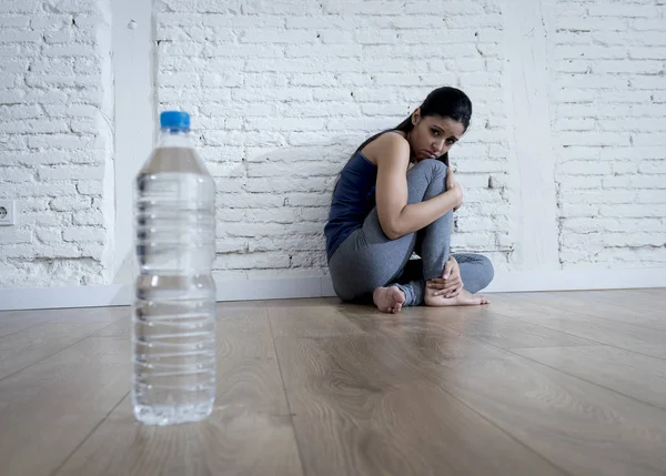 Mujer o niña adolescente sentada en el suelo sola preocupada en casa sufriendo un trastorno alimenticio nutricional — Foto de Stock