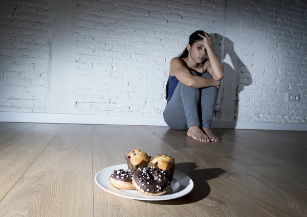Nezdravý cukr koblihy a vdolky a pokušení žena nebo dospívající dívka sedící na zemi — Stock fotografie