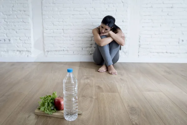 Mujer o niña adolescente sentada en el suelo sola preocupada en casa sufriendo un trastorno alimenticio nutricional — Foto de Stock