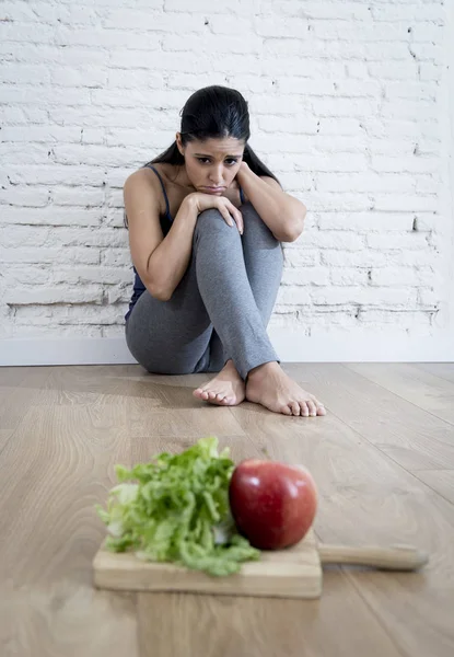 Mujer o niña adolescente sentada en el suelo sola preocupada en casa sufriendo un trastorno alimenticio nutricional — Foto de Stock