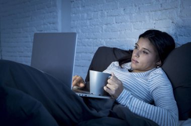 genç güzel İspanyol kadın evde yatakta dizüstü bilgisayarda çalışma gece mutlu