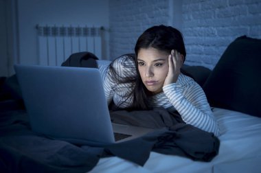 kadın yatakta sıkılmış ve dizüstü bilgisayar ile yorgun eve yatak odası çalışma, pijama