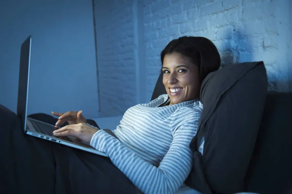 Wanita muda Hispanik di tempat tidur di rumah tertawa bahagia di komputer laptop di malam hari — Stok Foto