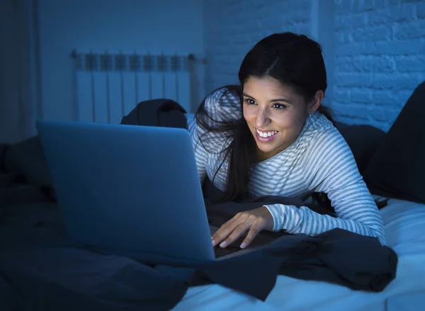 Jeune belle femme hispanique sur le lit à la maison riant heureux sur ordinateur portable la nuit — Photo
