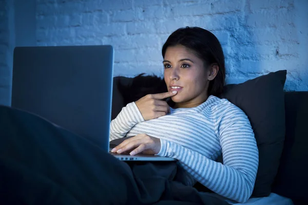 年轻美丽的西班牙裔女人，在床上在家里快乐便携式电脑夜间工作 — 图库照片