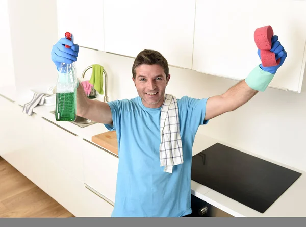 Молодий щасливий чоловік тримає пляшку миючого розпилювача і губку в рукавичках посміхаючись впевнено — стокове фото