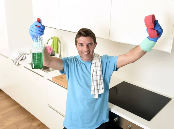 Młody człowiek szczęśliwy gospodarstwa prania detergentu sprayem i gąbka w rękawice uśmiechający się pewnie — Zdjęcie stockowe