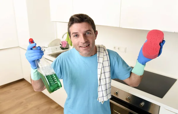 Joven feliz hombre celebración lavado detergente spray botella y esponja en guantes sonriendo confiado — Foto de Stock