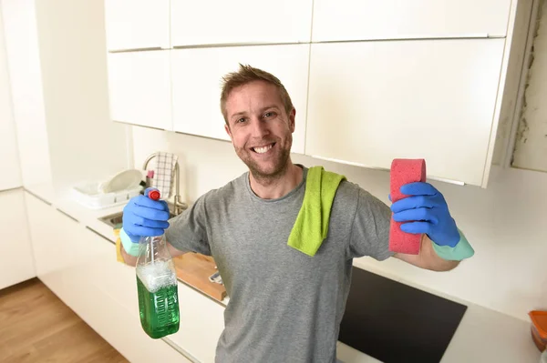 Joven feliz hombre en guantes de lavado de goma celebración detergente limpieza spray y esponja sonriente — Foto de Stock