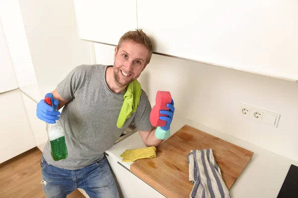 Young happy man in rubber washing gloves holding detergent cleaning spray and sponge smiling — Stock Photo, Image