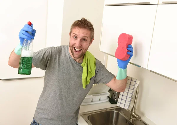 Joven feliz hombre en guantes de lavado de goma celebración detergente limpieza spray y esponja sonriente — Foto de Stock