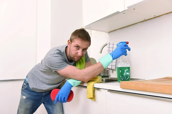 young sad frustrated man washing and cleaning home kitchen sink