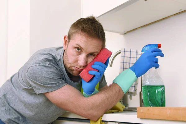 young sad frustrated man washing and cleaning home kitchen sink