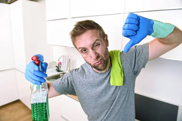 Young sad man in rubber gloves cleaning with detergent spray washing and making home kitchen sink — Stock Photo, Image