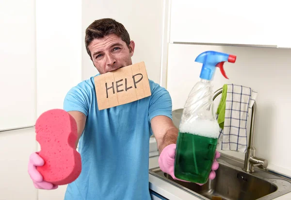 Брудний чоловік в стресі при митті рукавичок тримає губку і пляшку для розпилення миючих засобів, просячи допомоги — стокове фото
