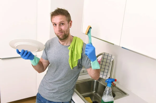 Sad and frustrated man washing the dishes and making home kitchen sink clean feeling tired — Stock Photo, Image