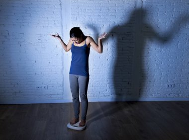 üzgün ve umutsuz genç fit ve ince kadın vücut ağırlığı ile büyük sinirli gölge ölçekte kontrol ışık 