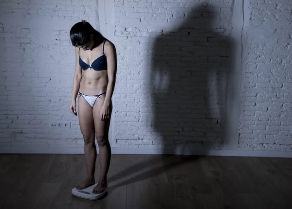 Unga passform och smal kvinna kontrollera kroppsvikt på skala med stora edgy skugga ljus sorgligt och desperat — Stockfoto