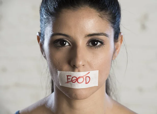 Primer plano cara de joven hermosa mujer latina triste con la boca sellada en cinta adhesiva con el texto sin comida — Foto de Stock