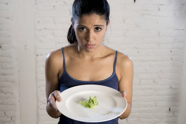 Mujer joven sosteniendo el plato con lechuga ridícula como su símbolo de alimentación de la dieta loca trastorno nutricional —  Fotos de Stock