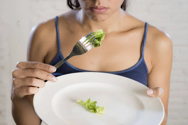 Young woman holding dish with ridiculous lettuce as her food symbol of crazy diet nutrition disorder — Stock Photo, Image