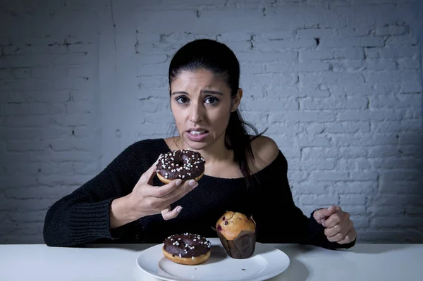 Vrouw die aan de tabel schuldgevoel vergeten dieet eten schotel vol met ongewenste suikerhoudende ongezond voedsel zit — Stockfoto