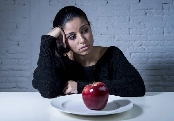 Young woman or teen looking apple fruit on dish as symbol of crazy diet in nutrition disorder — Stock Photo, Image