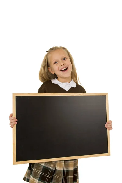 Pequeña hermosa rubia colegiala sonriendo feliz y alegre celebración y mostrando pequeña pizarra en blanco — Foto de Stock