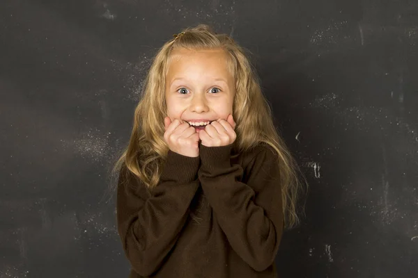 Милая школьница в форме смеется взволнованная перед школьной доской, улыбаясь счастливой — стоковое фото