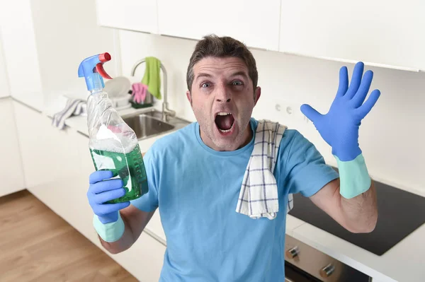 Молодий ледачий прибиральник будинку миє та прибирає кухню пляшкою з розпилювачем — стокове фото